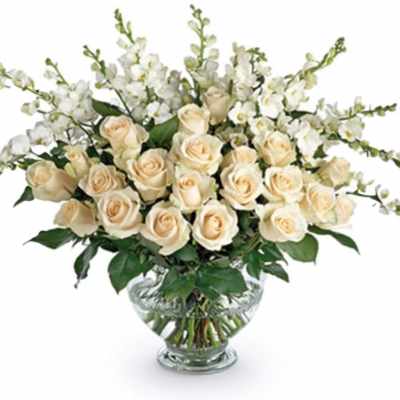 Cream roses and white orchids in a clear glass vase