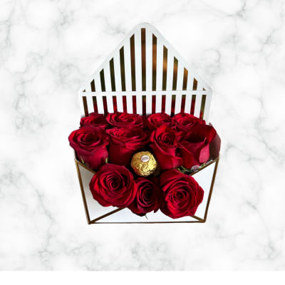 Red roses in a geometric gift box with a gold chocolate