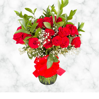 Red roses in a glass vase with baby's breath and a red ribbon