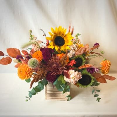 Autumn floral arrangement with sunflowers, chrysanthemums, and a wooden box