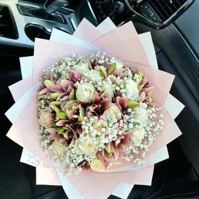 Bouquet of pink lilies and cream roses wrapped in pastel paper