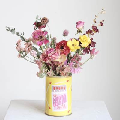 Mixed pink and yellow flowers in a yellow tin container