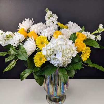 Yellow and white flowers arranged in a glass vase