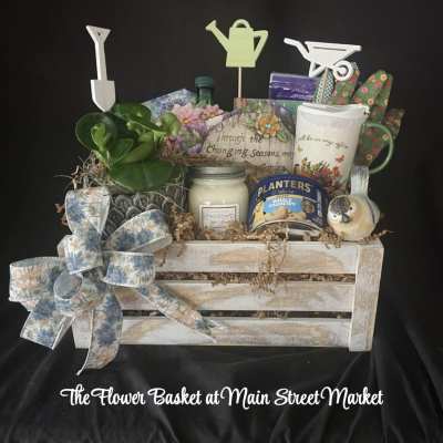 Gift basket with a potted plant, candle, mug, snacks, and garden decor