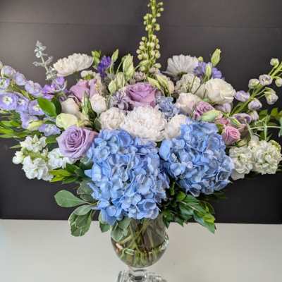 Lavender and blue floral arrangement in a clear glass vase