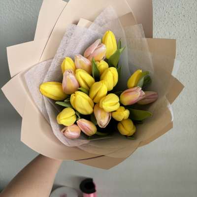Bouquet of yellow and blush tulips wrapped in beige paper