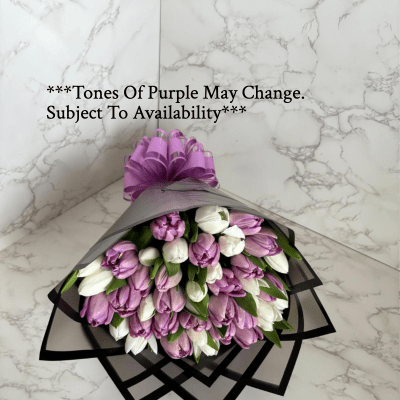 Bouquet of purple and white tulips wrapped in black paper with a purple bow