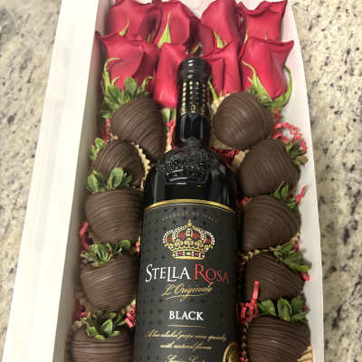 Gift box with red roses, chocolate-covered strawberries, and a wine bottle