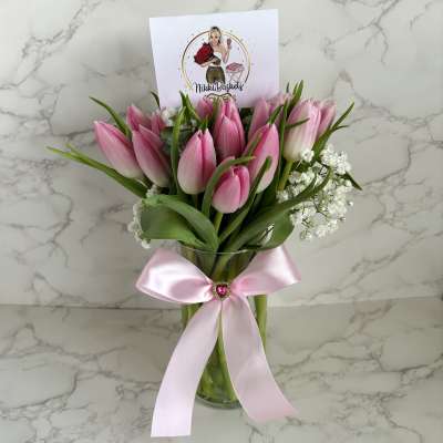 Pink tulips in a glass vase with a pink ribbon