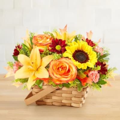 Basket arrangement with sunflowers, roses, lilies, and red daisies