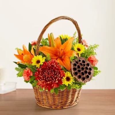 Basket arrangement with orange lilies, yellow daisies, and red chrysanthemums