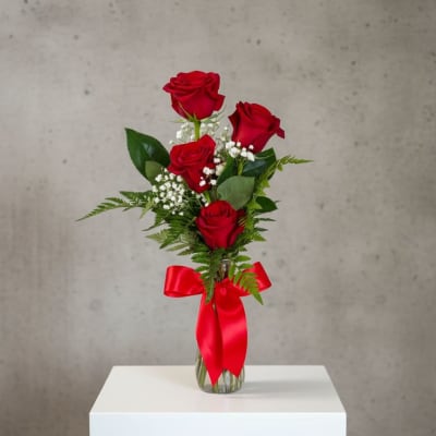 Red roses in a clear glass vase with a red ribbon