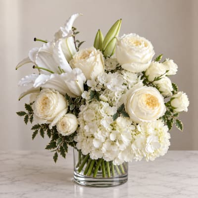 White roses and lilies arranged in a clear glass vase