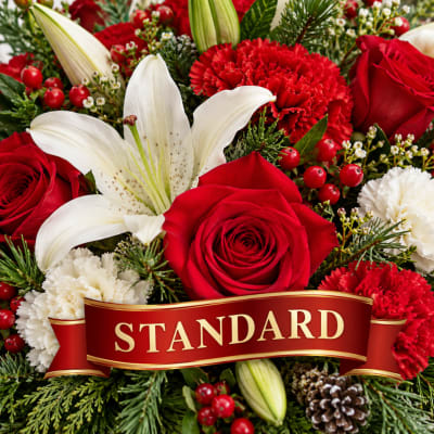 Red roses, white lilies, and carnations in a holiday arrangement with a STANDARD ribbon