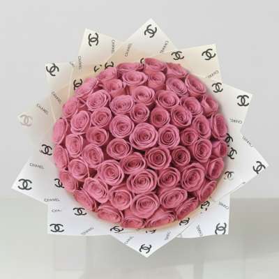 Bouquet of pink roses wrapped in Chanel-branded paper