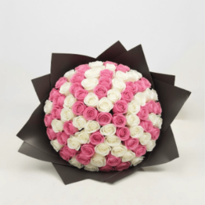 Bouquet of pink and white roses wrapped in dark paper