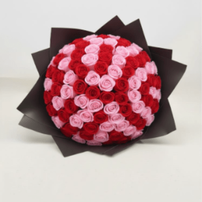 Round bouquet of red and pink roses wrapped in dark paper
