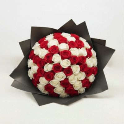 Round bouquet of red and white roses wrapped in dark paper
