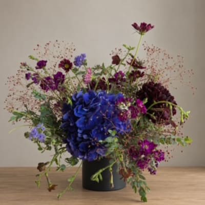 Blue and purple floral arrangement in a black vase