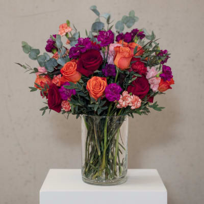 Bouquet of red, orange, and purple flowers in a clear glass vase