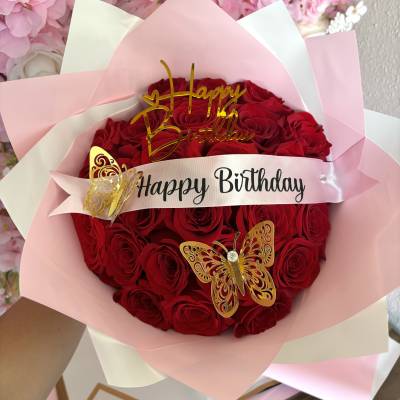 Bouquet of red roses wrapped in pink paper with a birthday ribbon