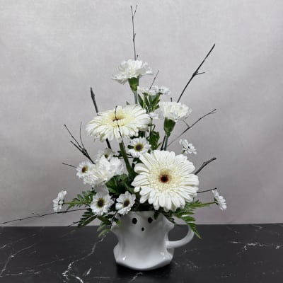 White gerbera daisies and carnations arranged in a white ceramic vase