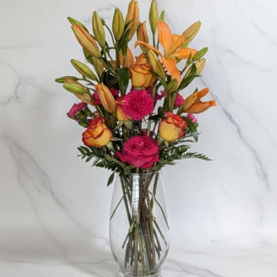 Bouquet of orange lilies and pink roses in a clear glass vase