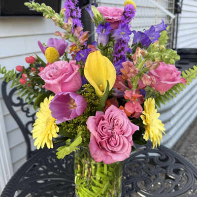 Mixed bouquet of pink, purple, yellow, and red flowers in a glass vase