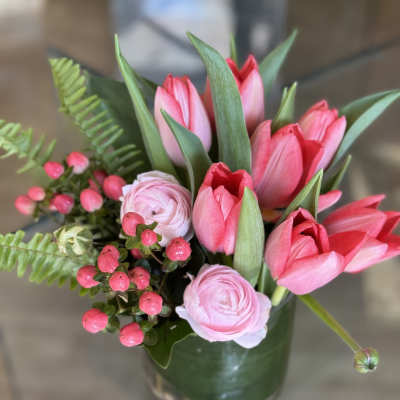 Pink tulips and pale pink ranunculus in a glass vase
