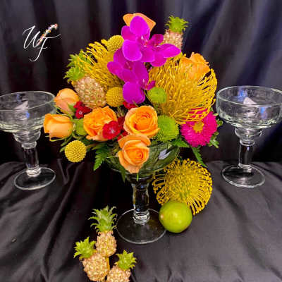 Tropical floral arrangement with roses and orchids in a glass vase