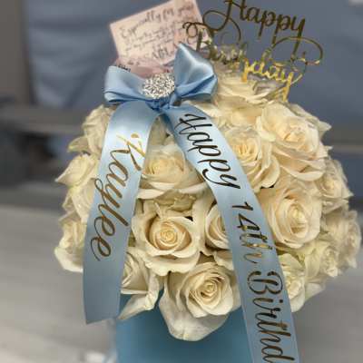 Cream rose arrangement in a blue hat box with a birthday ribbon