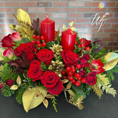 Red roses arranged with two red candles and gold accents