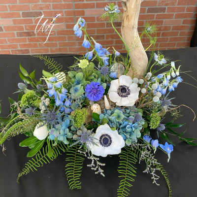 Blue and white floral arrangement with driftwood and shells