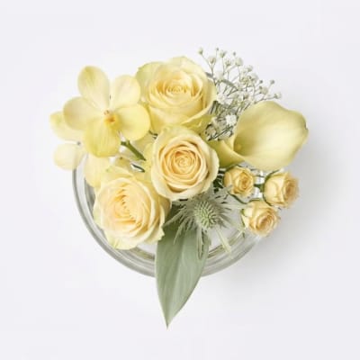 Yellow roses and calla lilies in a clear glass bowl