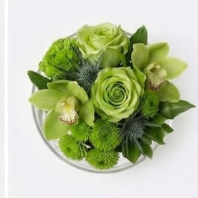 Green floral bouquet with roses and orchids in a clear vase