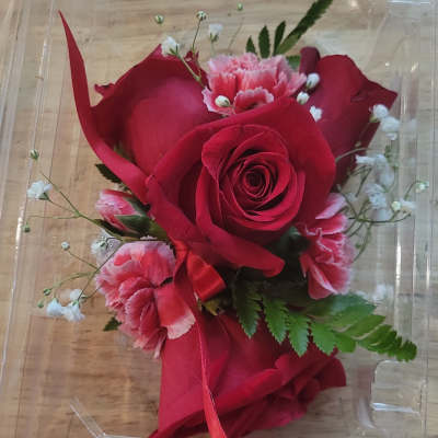 Red rose corsage with pink carnations in a clear plastic box