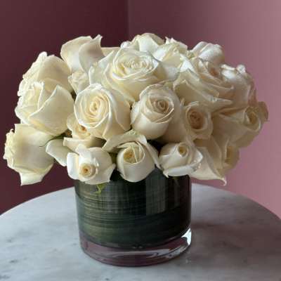 White rose bouquet in a glass vase on a round table