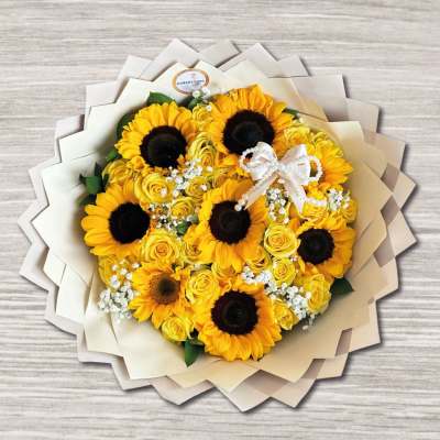 Bouquet of yellow sunflowers and roses with a white ribbon