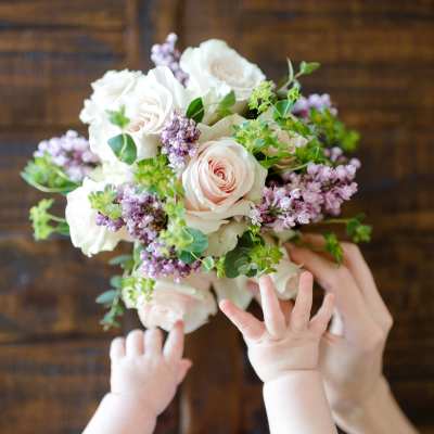 Handheld bouquet of pale pink and white roses with lilac flowers