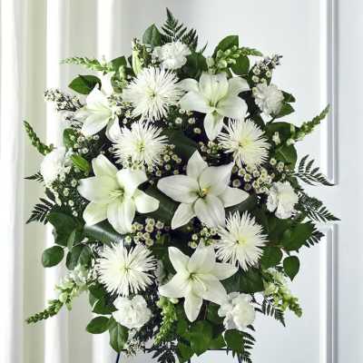 White floral standing spray on an easel with lilies and spider mums