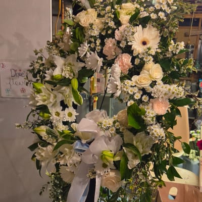 Large white floral wreath with ribbon and mixed blooms