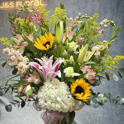 Mixed bouquet in a glass vase with sunflowers, lilies, and hydrangea