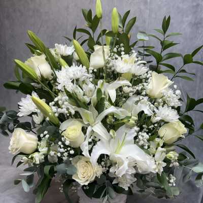 White lilies and roses arranged in a white basket
