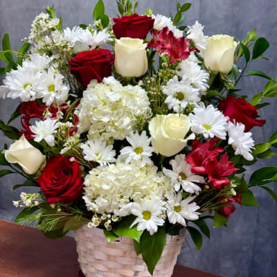Basket arrangement of red and white roses, daisies, and hydrangeas