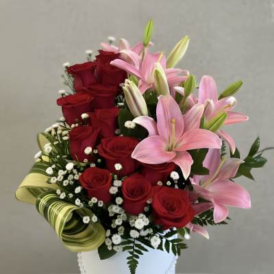Red roses and pink lilies in a white hatbox with a red ribbon