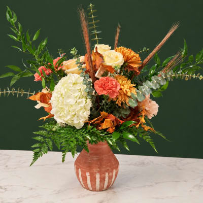 Autumn floral arrangement in a terracotta vase with hydrangea, roses, and mums