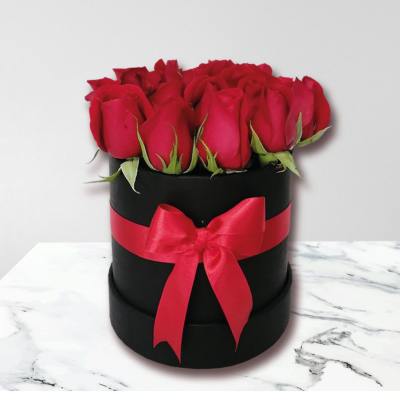 Red roses arranged in a black round box with a red ribbon