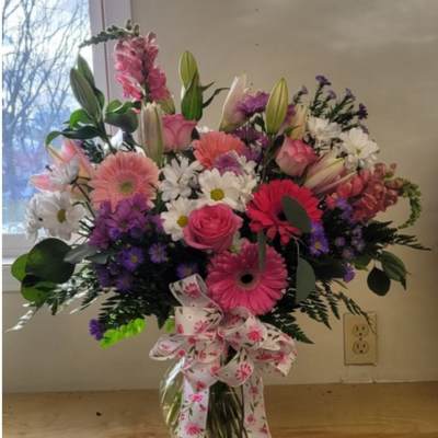 Pink and white mixed bouquet in a glass vase with a floral ribbon