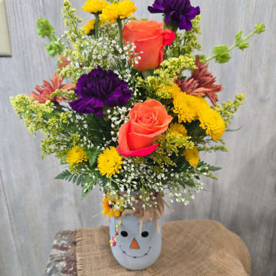 Colorful mixed flower arrangement in a snowman-themed container