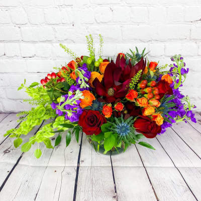 Colorful bouquet with red roses and purple flowers in a glass vase